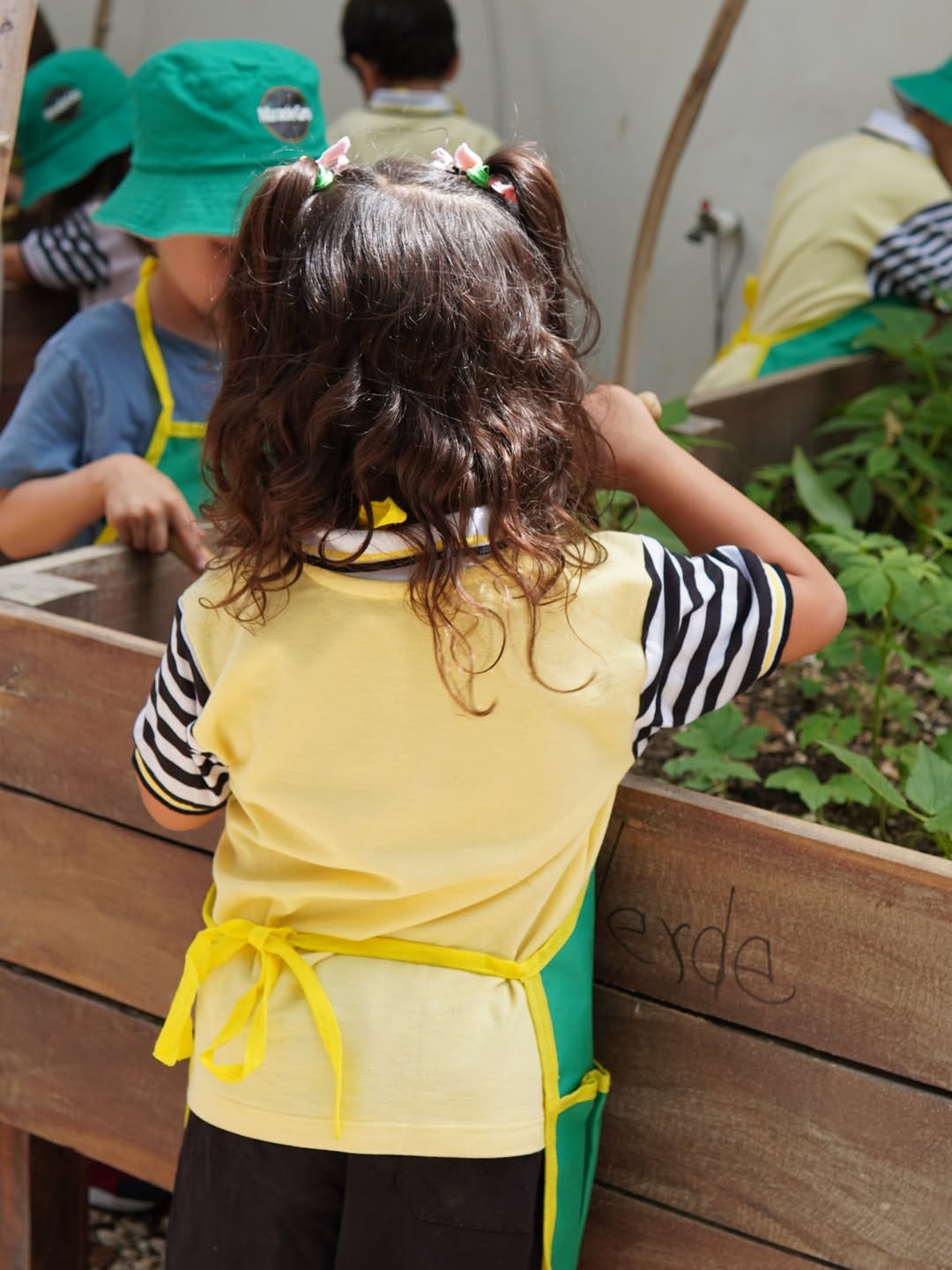 Una niña trabaja en una jardinera del huerto