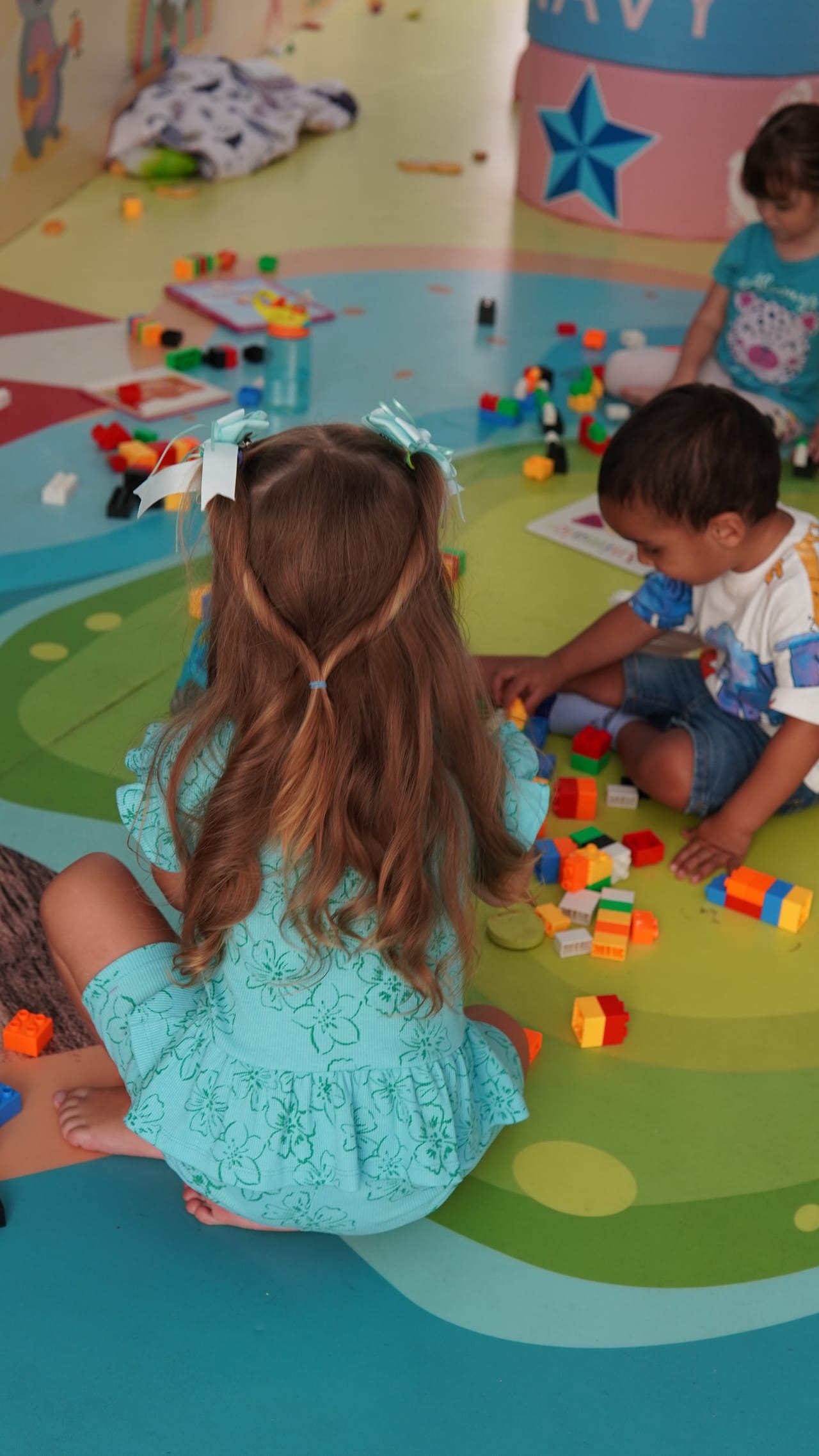 Niños juegan con bloques de colores en el piso del salón