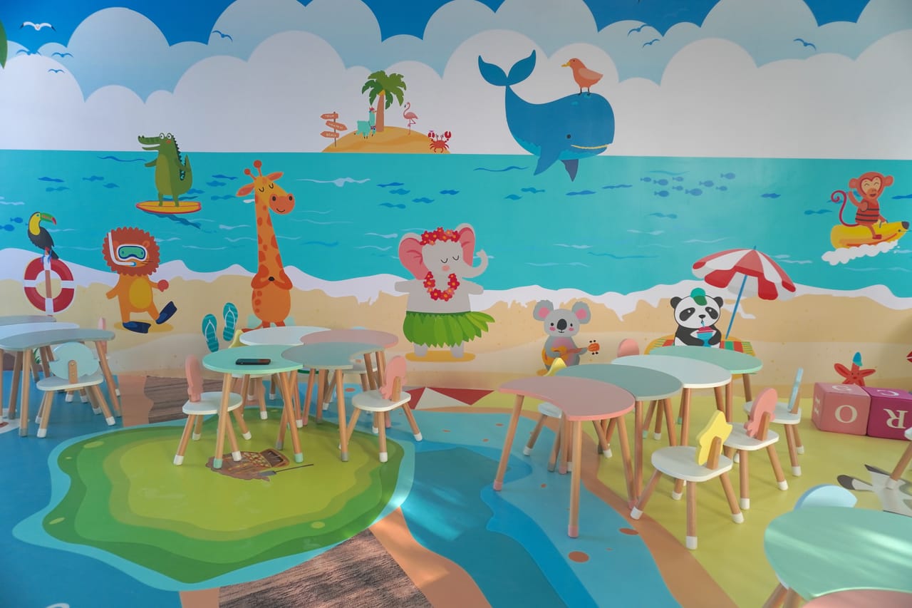 Salón con un mural de playa y mesas pequeñas