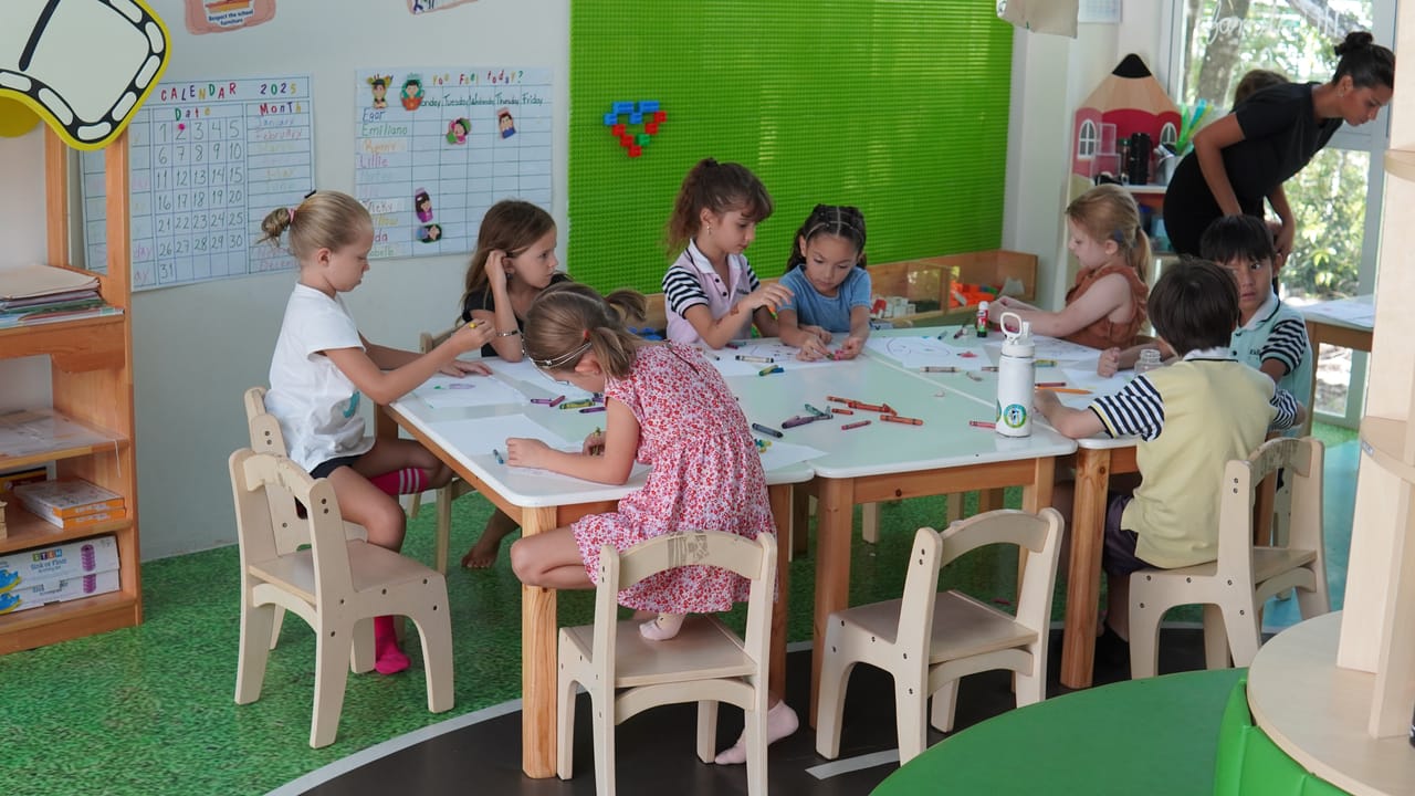 Alumnos dibujan en una mesa larga del salón