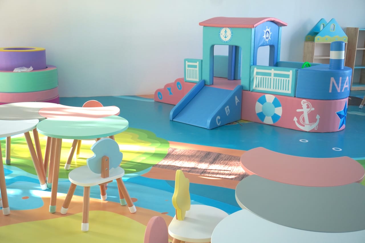 Salón con un barco de juego y mesas de colores