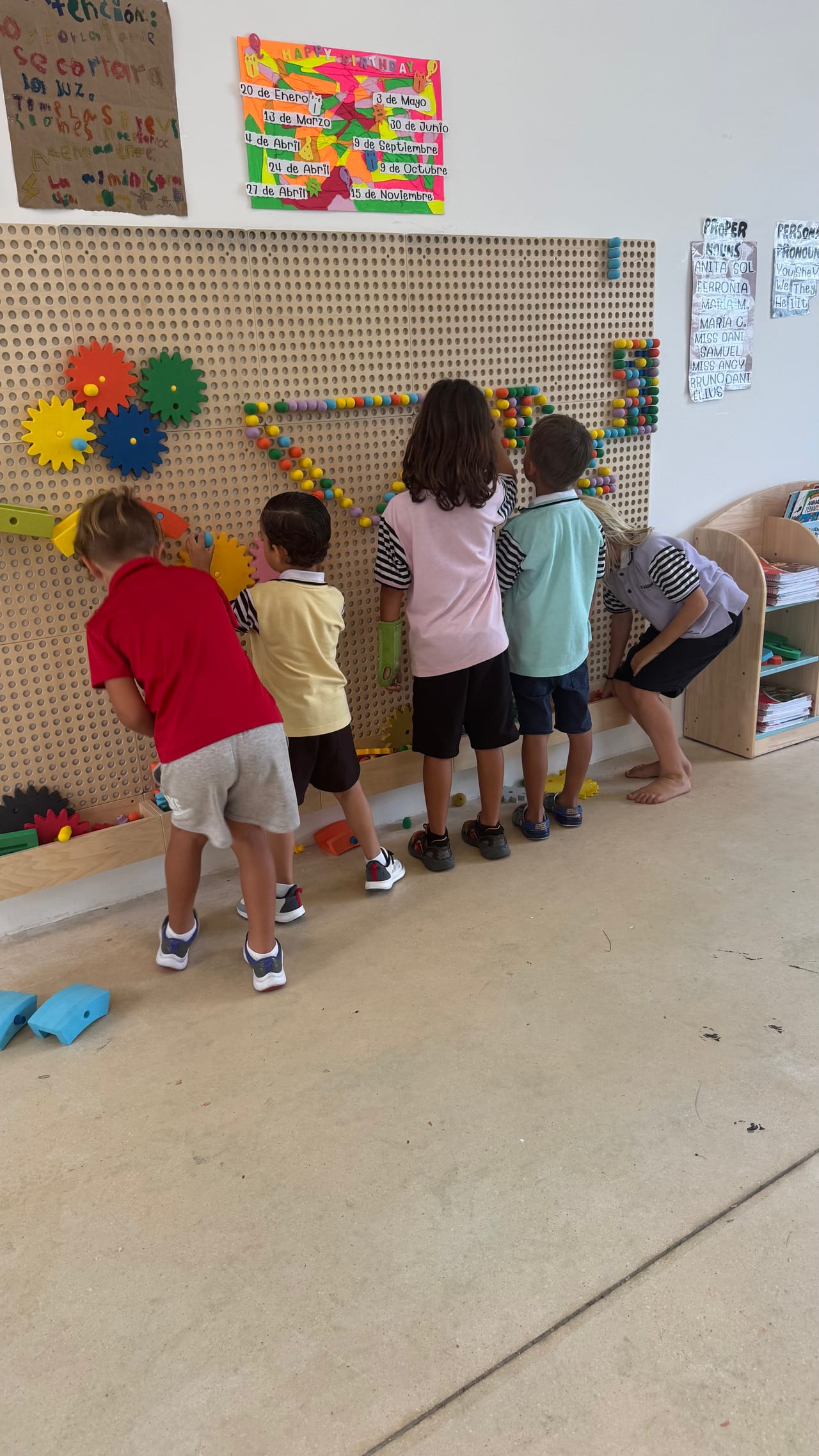 Niños arman engranes en un tablero de pared