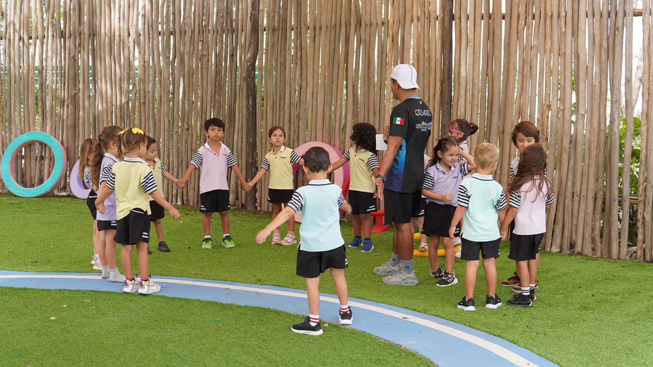 Niños de preescolar hacen una ronda en el jardín con su profesor