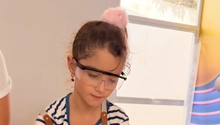 Una alumna con lentes de seguridad trabaja con madera