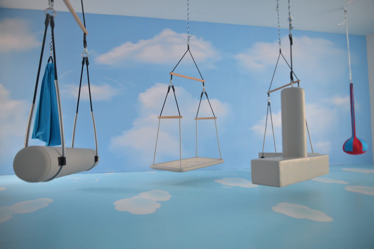 Salón sensorial con columpios y paredes pintadas de cielo