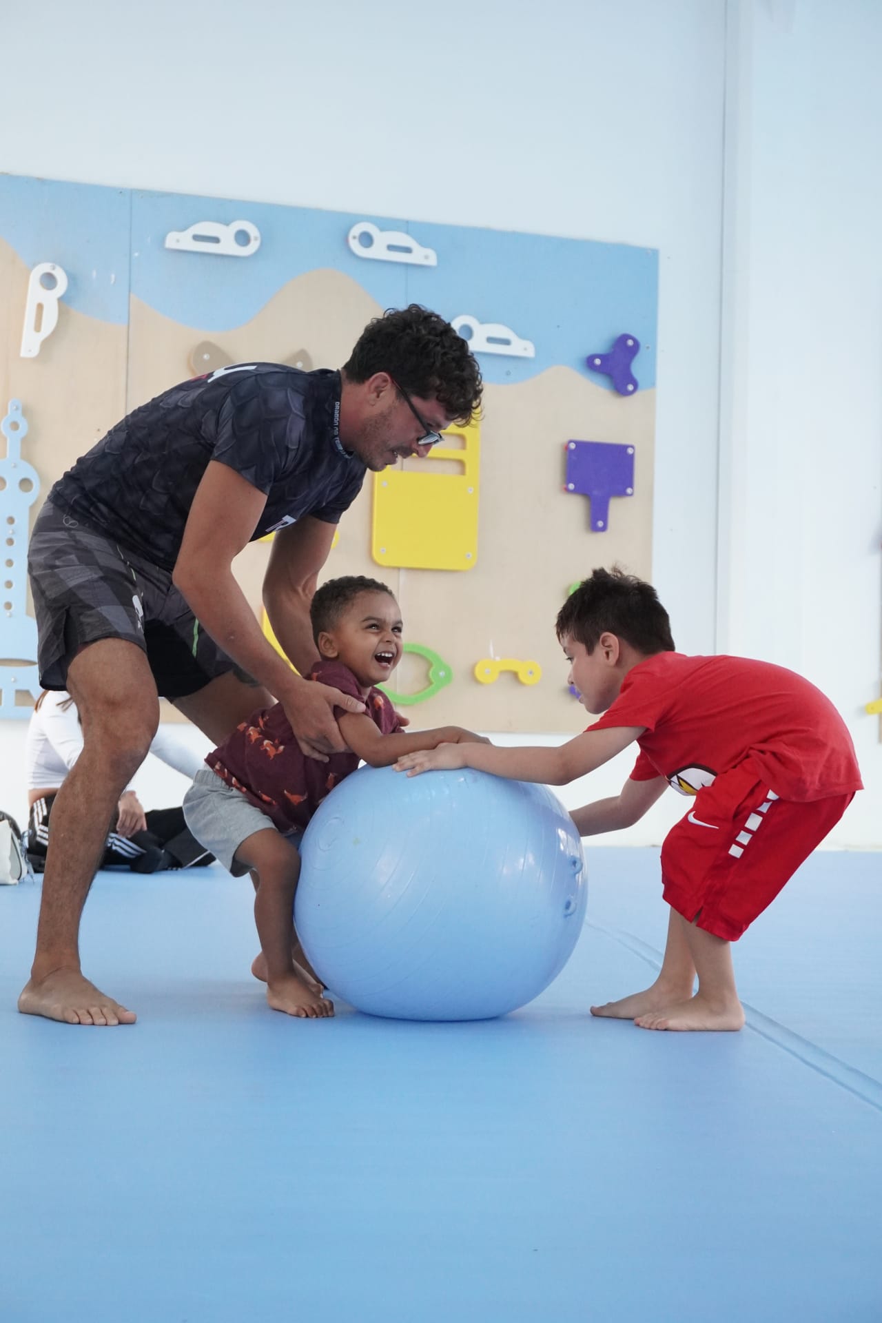 Un maestro y dos niños juegan con una pelota grande