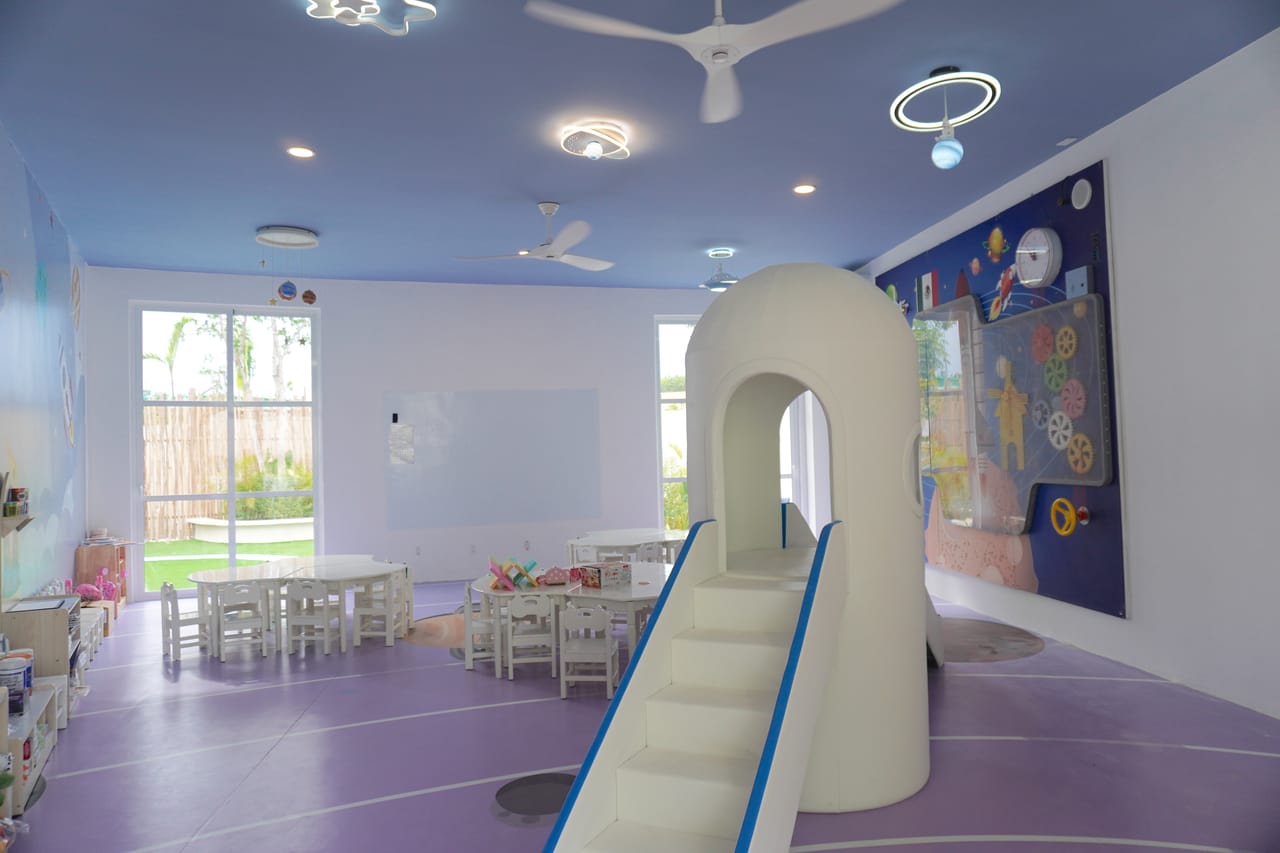 Salón con resbaladilla y mesas pequeñas
