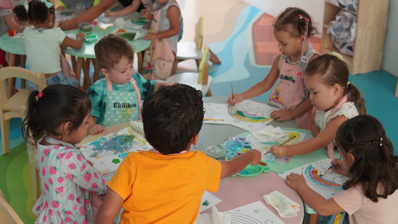 Niños de preescolar pintan juntos alrededor de una mesa