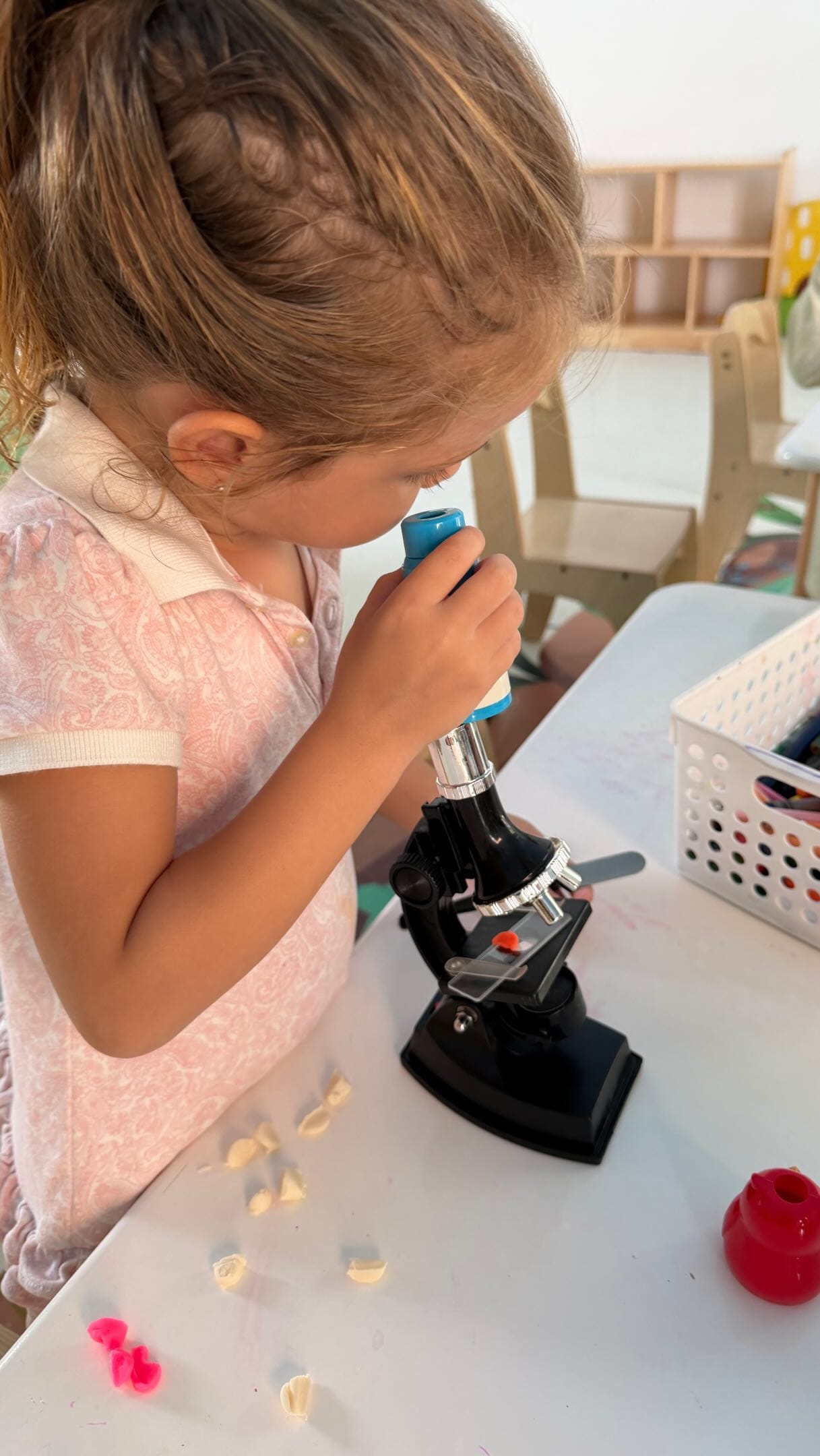 Una niña observa por un microscopio